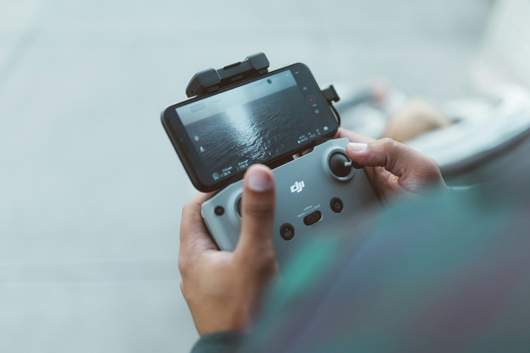 DJI-controller met smartphone tijdens het besturen van een drone, gebruikt om de compatibiliteit tussen DJI controllers en drones te illustreren