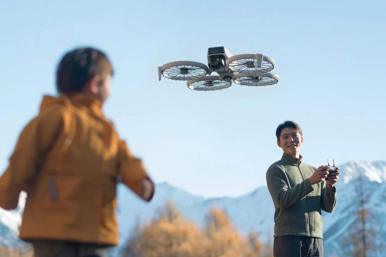 Een dronepiloot bestuurt een drone in open terrein, een situatie waarvoor een A1/A3-dronevliegbewijs vereist is in België