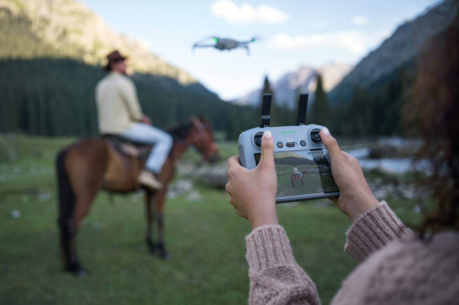 Drone piloot filmt ruiter te paard in berglandschap met DJI controller