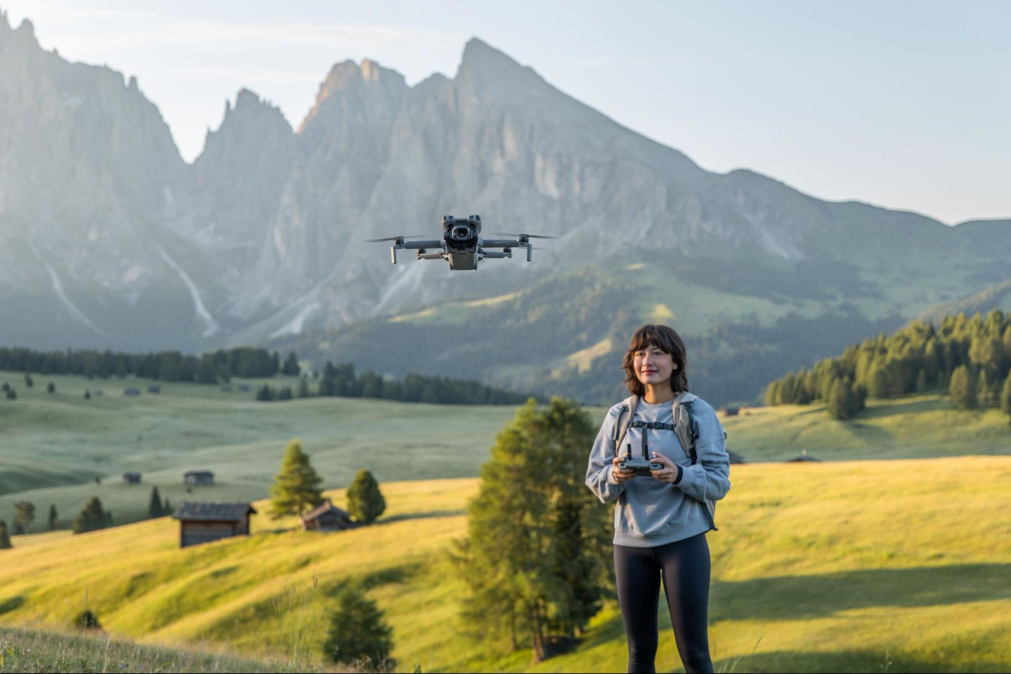 Dronepiloot bestuurt een drone in een bergachtig landschap.
