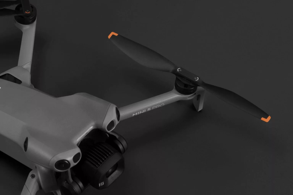 Close-up van een DJI Mini 5 Pro met uitgeklapte propeller met oranje tip.